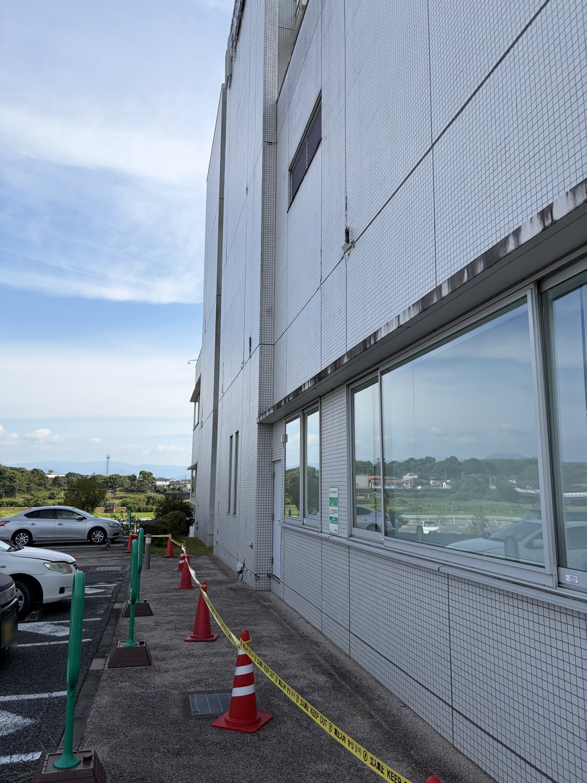 外壁の落下のおそれからカラーコーンとテープで立入規制された建物際